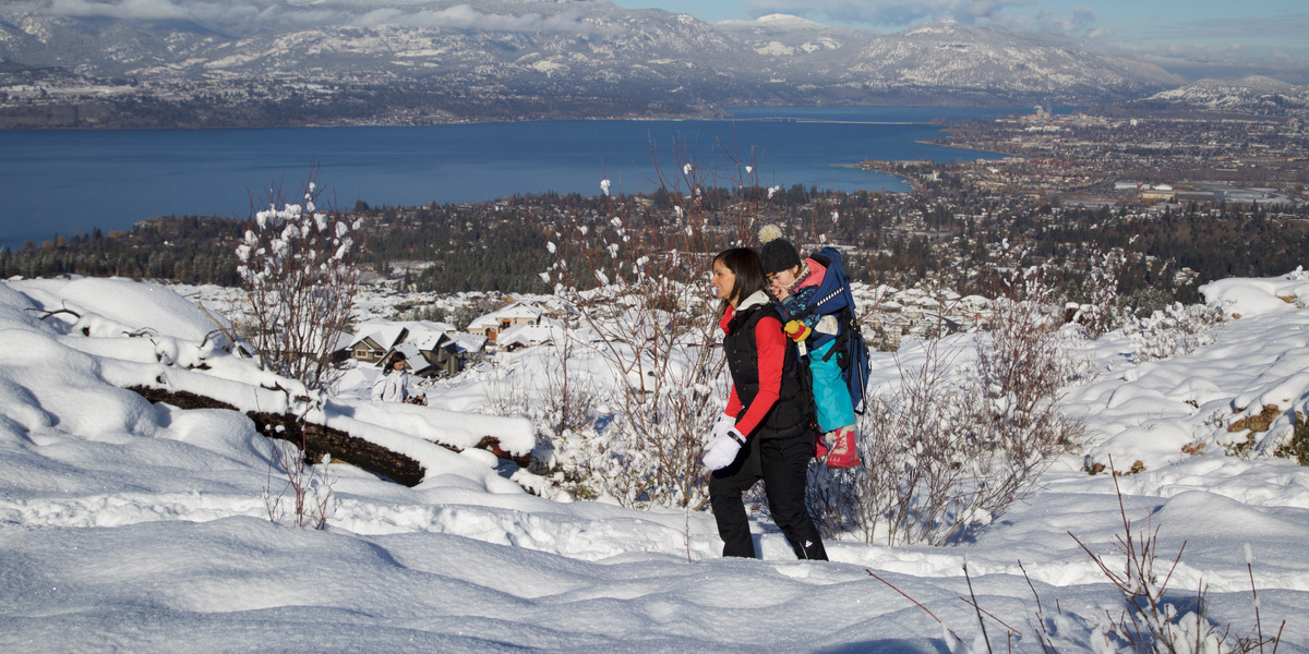 A mom with a baby in a backpack hiking on a snowy day at Kuipers Peak.