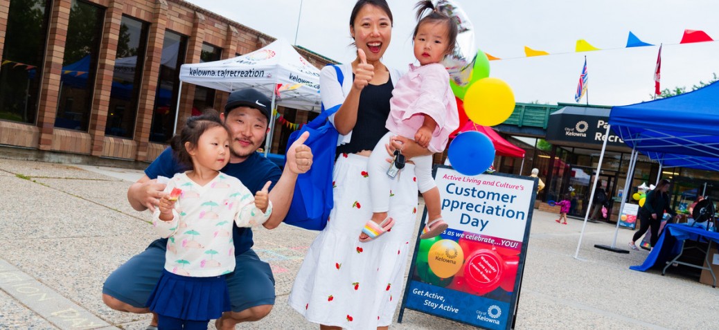 A smiling family standing in front of PRC beside a Customer Appreciation Day sign