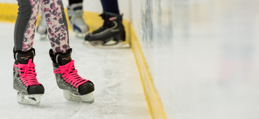 Hockey skates with bright pink laces on the ice rink