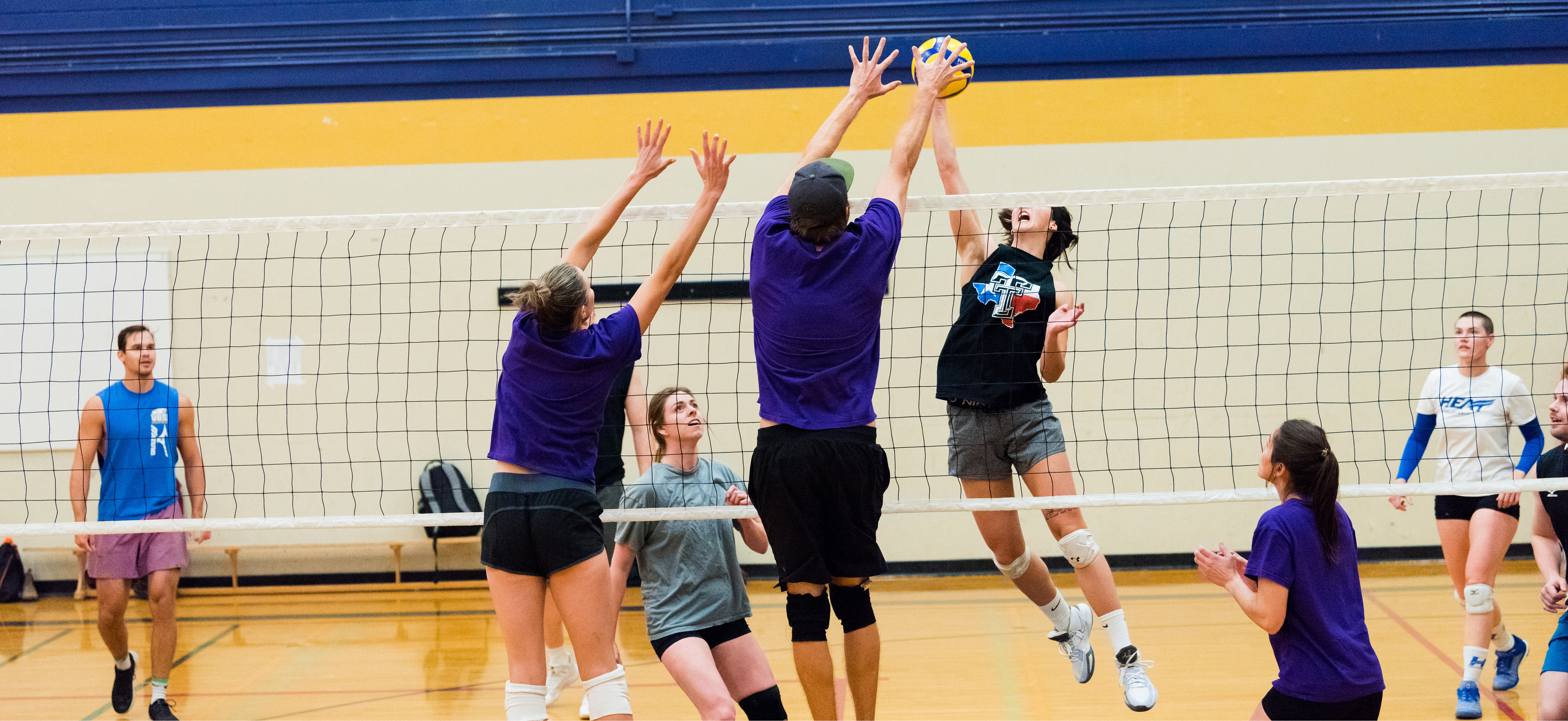 Volleyball league players jumping to block the ball at the net